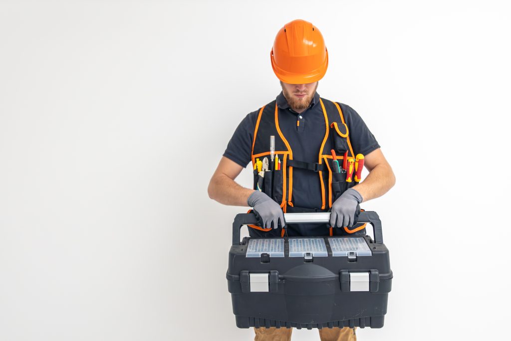 1-male-builder-electrical-engineer-overalls-helmet-holds-toolbox-hands-space-text-scaled